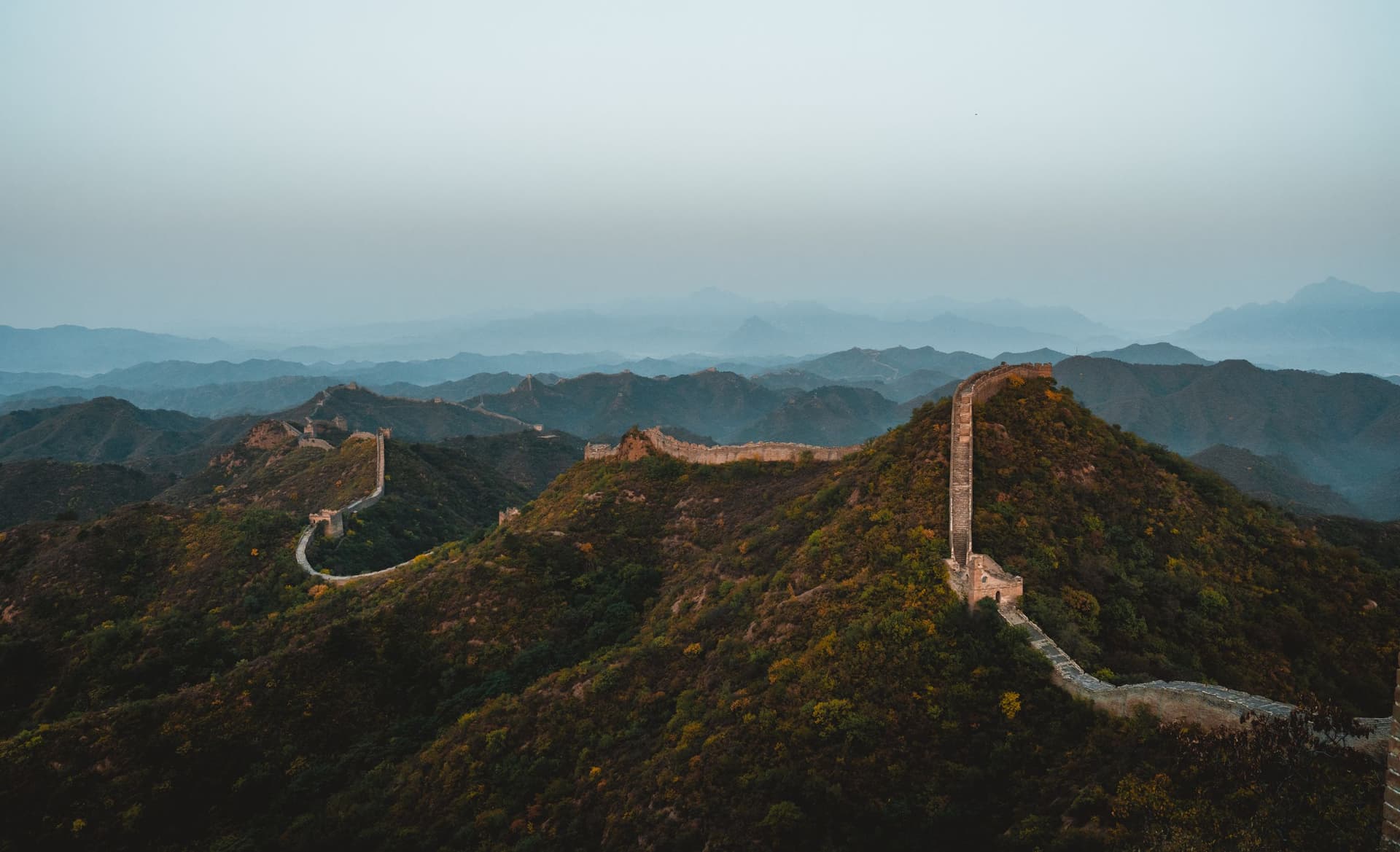 The Great Wall follows a ridge through the hills at dusk.